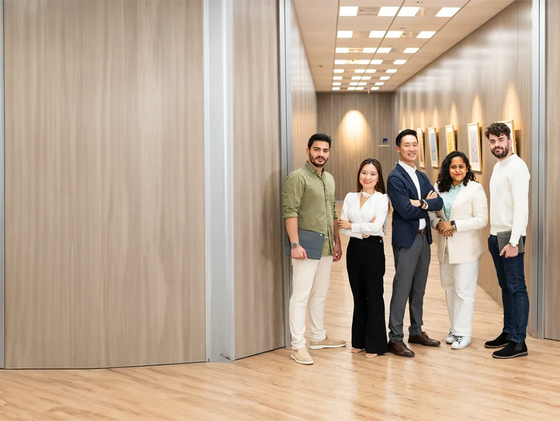 Five GLOBIS MBA students standing together in an office hallway with wood paneling, smiling